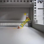 Erdungspunkt M6 am Boden des 19"-Netzwerkschranks SRK mit grün-gelbem Spiral-Erdungskabel und Erdungssymbol